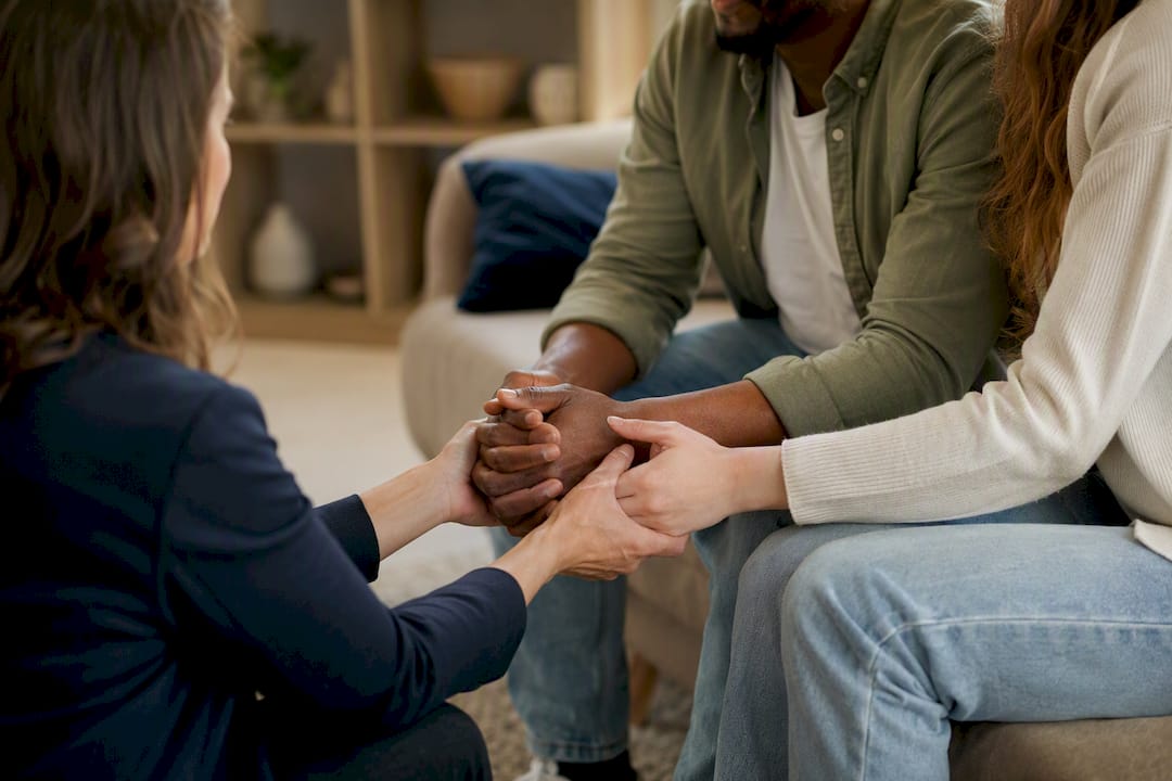 Therapist hands guiding couple's fingers in therapy